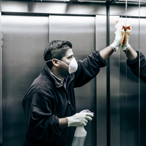 coronavirus. cleaning staff disinfecting elevator to avoid contagion